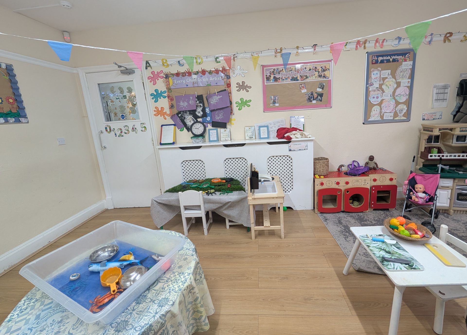 Bright classroom play area with toys, tables, chairs, and colorful wall decorations