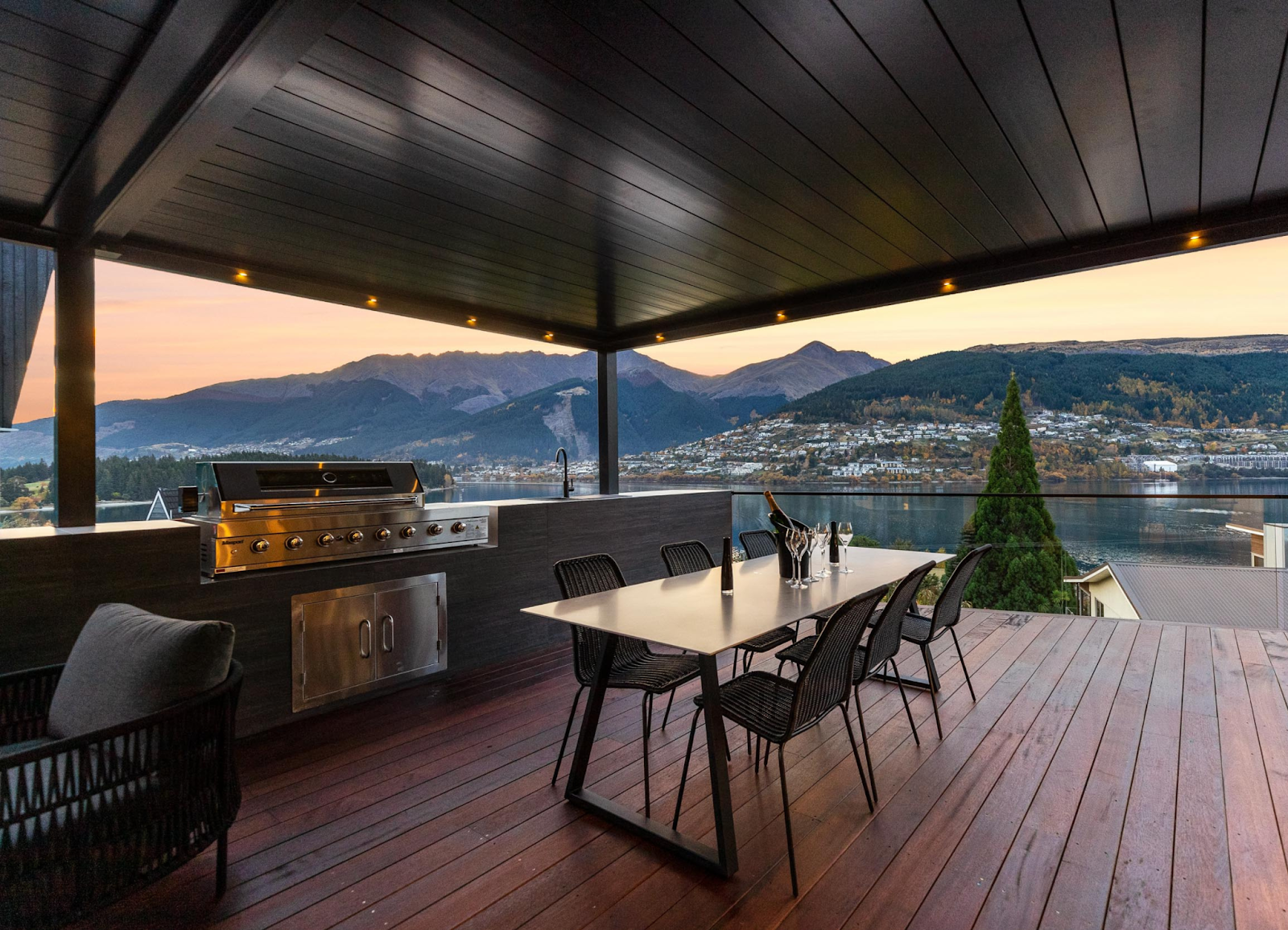 There is a table and chairs on the deck with a view of the mountains.