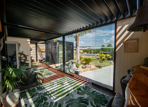 A living room with a lot of windows and a rug on the floor.