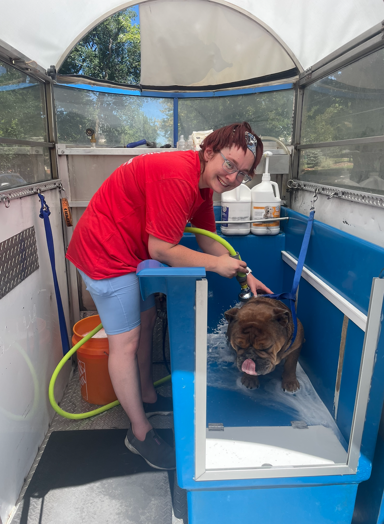 A man standing next to a dog in front of a mobile dog wash
