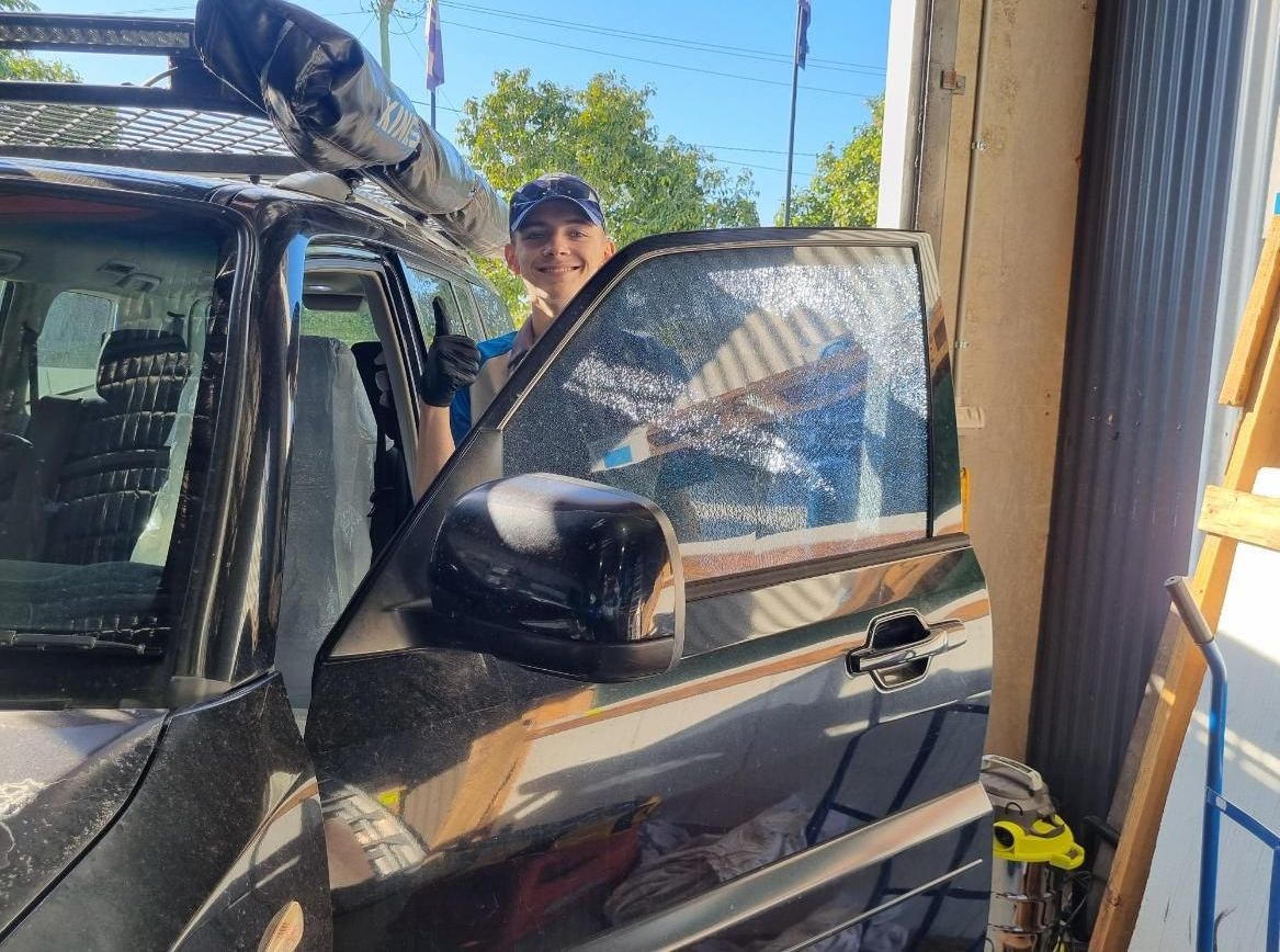 A Man Is Standing Next To A Car With A Surfboard On Top Of It — Australian Specialised Machinery Glass In Mount Louisa, QLD