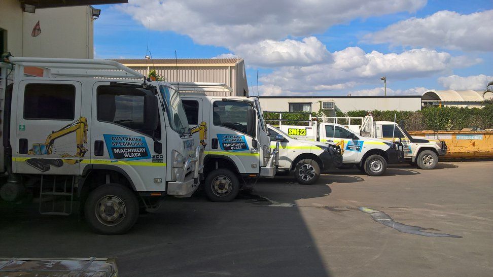 A Row Of Trucks Are Parked In A Parking Lot — Australian Specialised Machinery Glass In Mount Louisa, QLD
