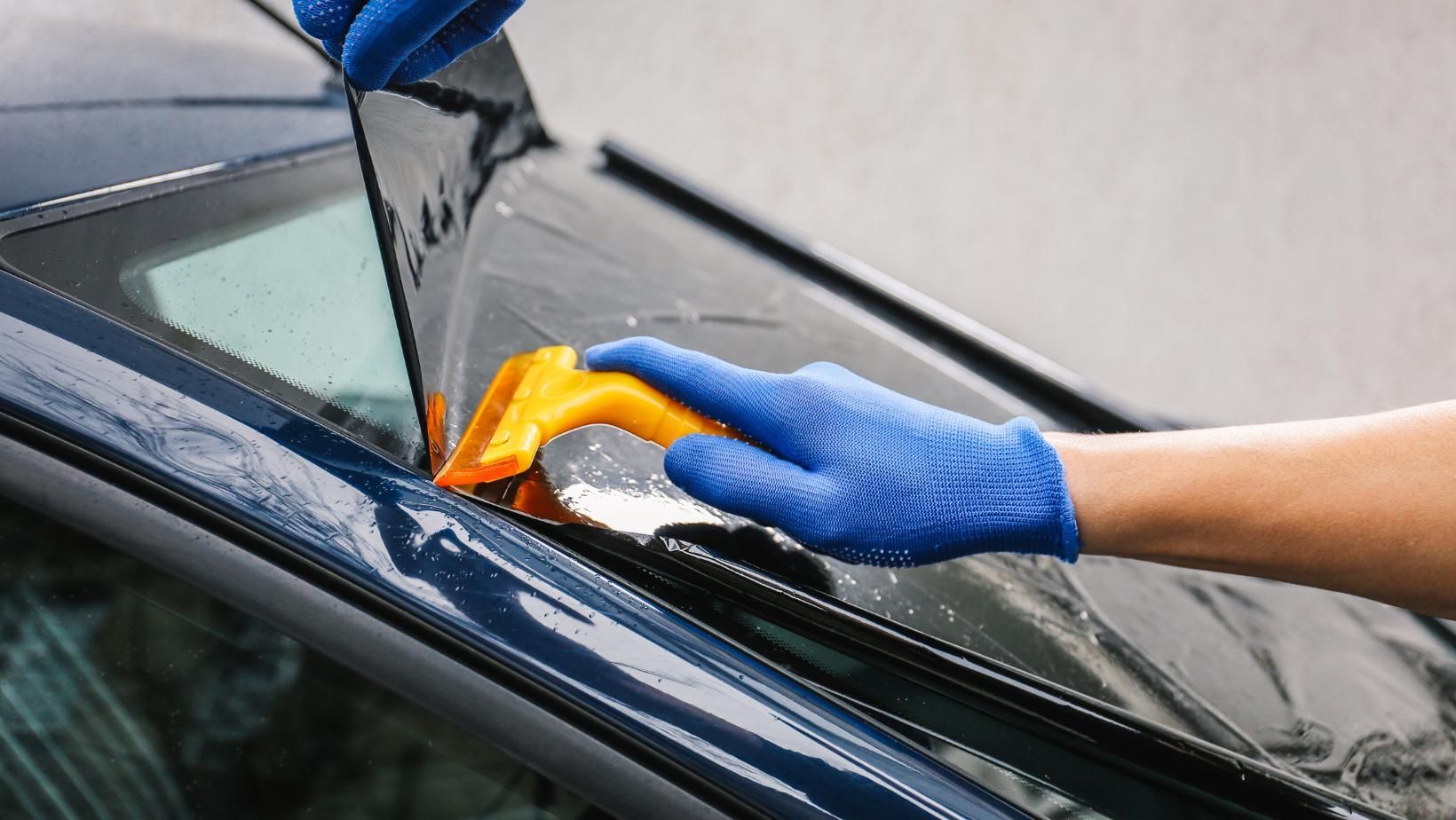 A Person Wearing Blue Gloves Is Cleaning The Windshield Of A Car — Australian Specialised Machinery Glass In Mackay, QLD