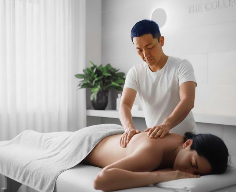 Man giving massage to person lying face down on a massage table. Interior spa setting.