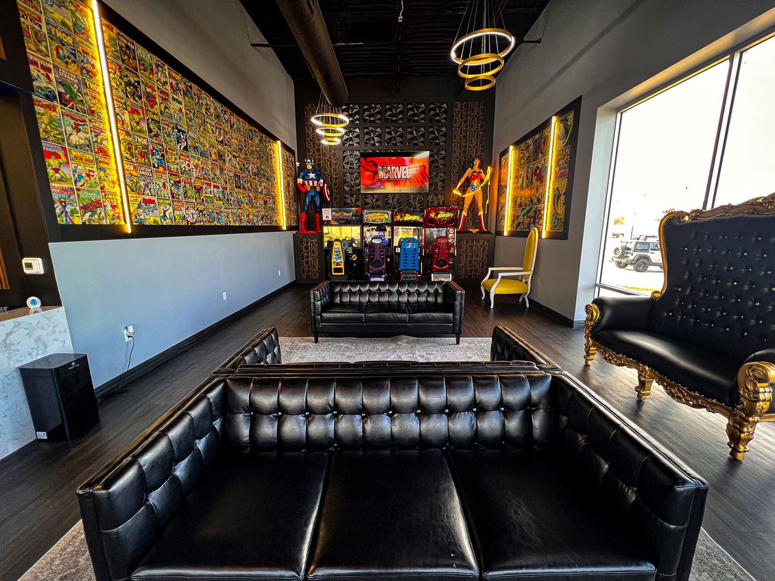 Stylish lounge with black leather seating, colorful wall art, and large windows overlooking a city view