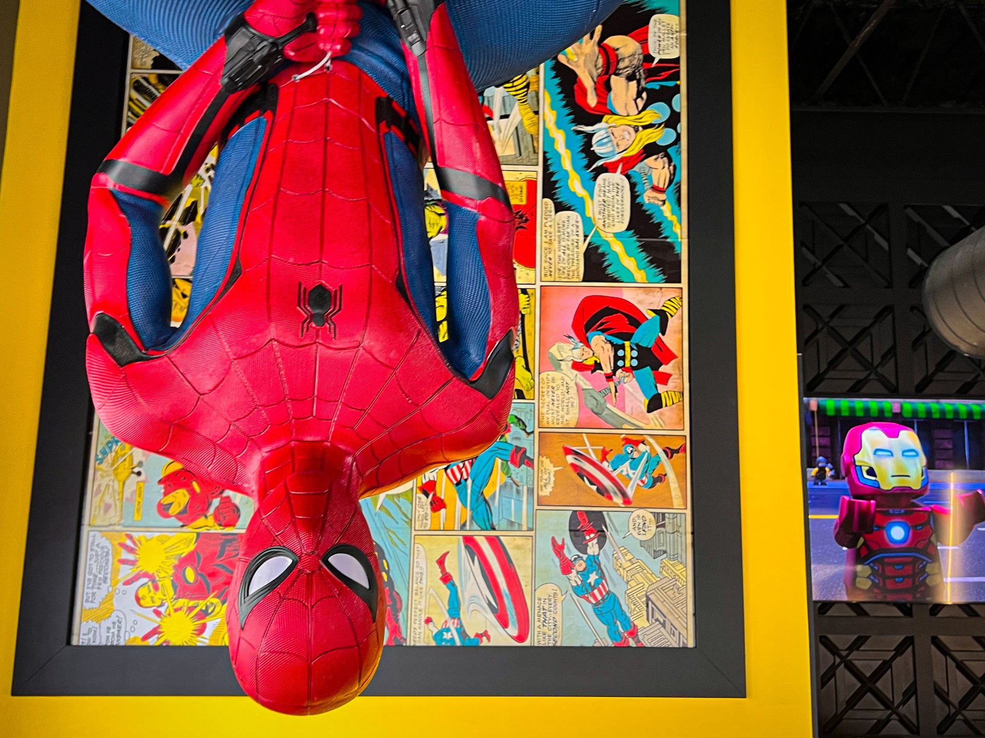 Spider-Man action figure on comic art display, with a small Iron Man figure beside it