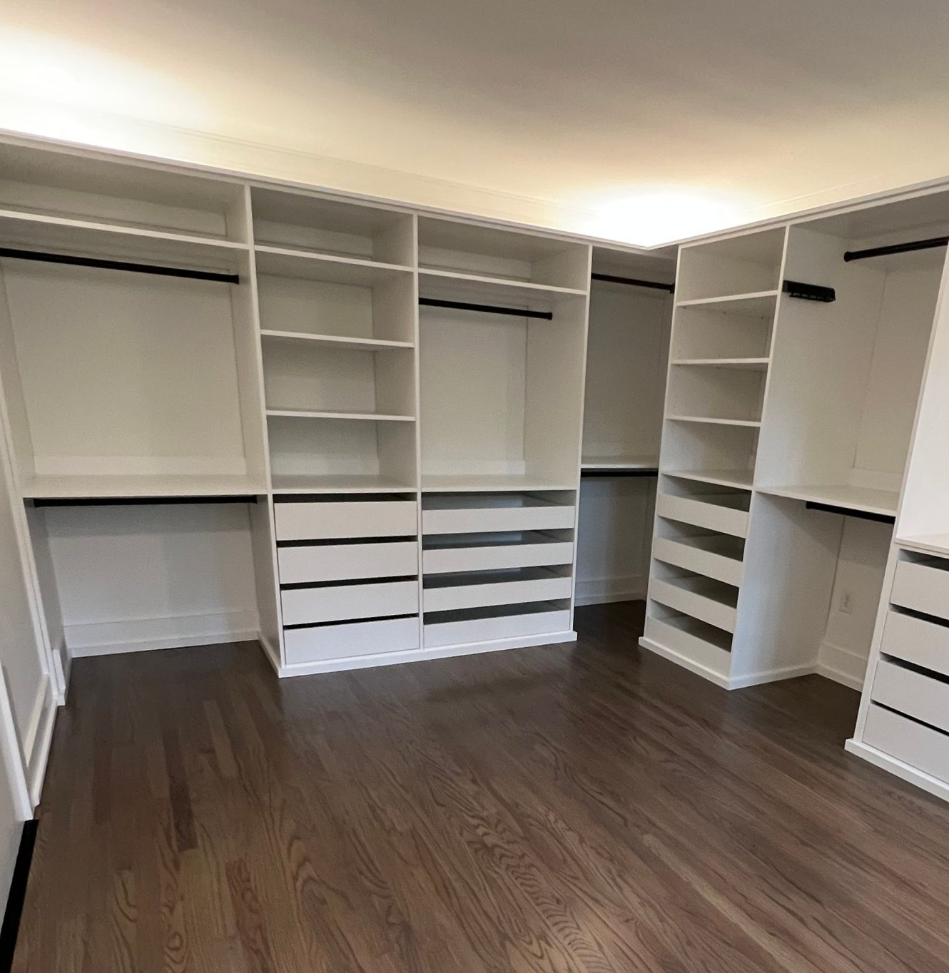A view of a custom closet with built in shelves, wood floors and custom lighting