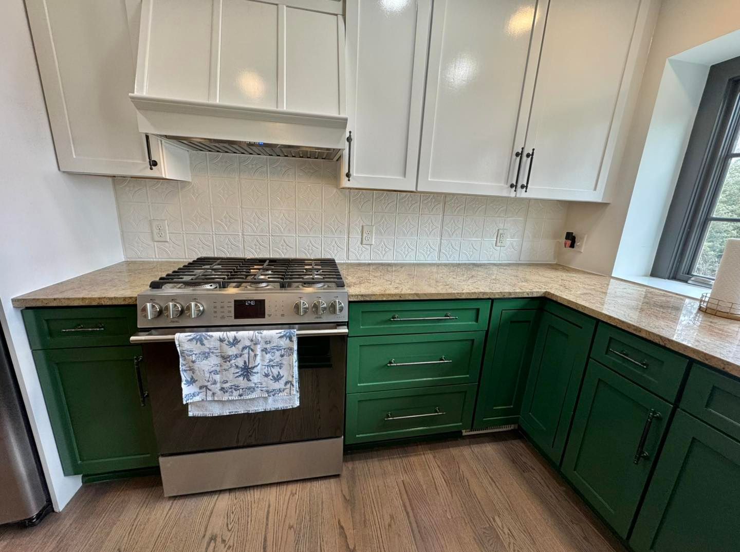 A kitchen featuring white upper cabinets, a light stone countertop, green lower cabinets, and a stainless steel stove.