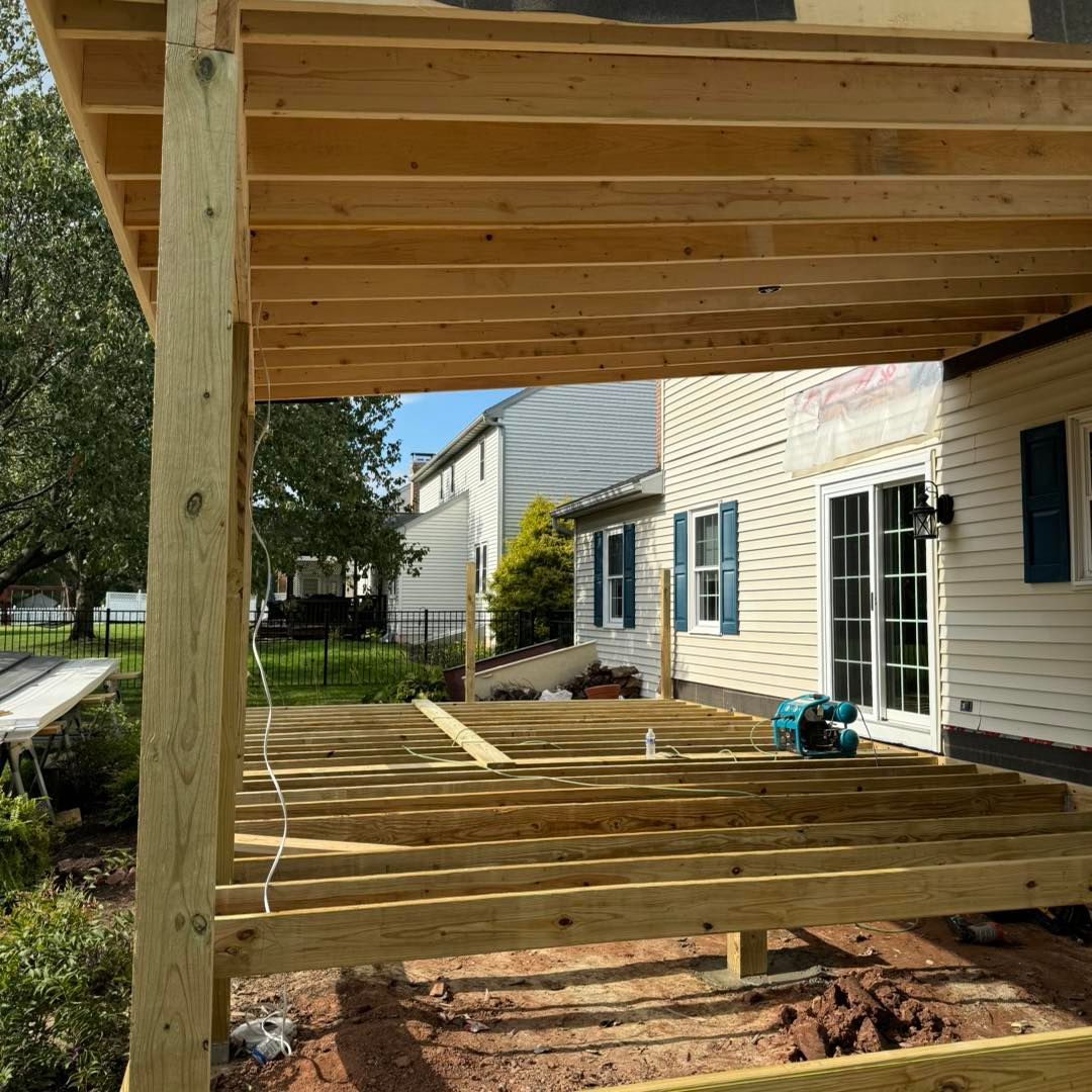 Wooden deck construction in progress next to a suburban house with a sliding glass door and tan siding.