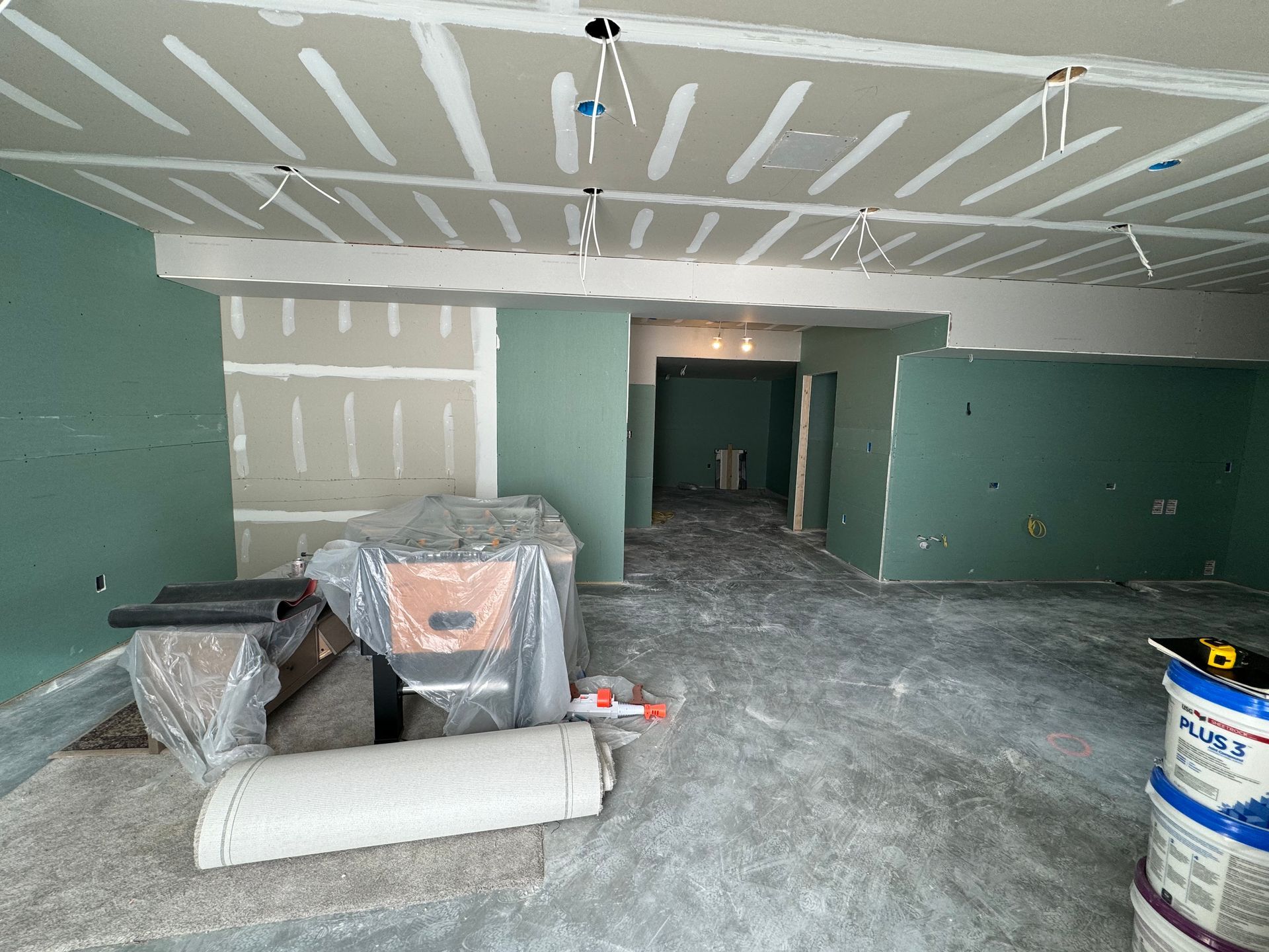 A finished basement with white kitchen cabinetry, a stainless refrigerator, wood-look flooring, and a foosball table.