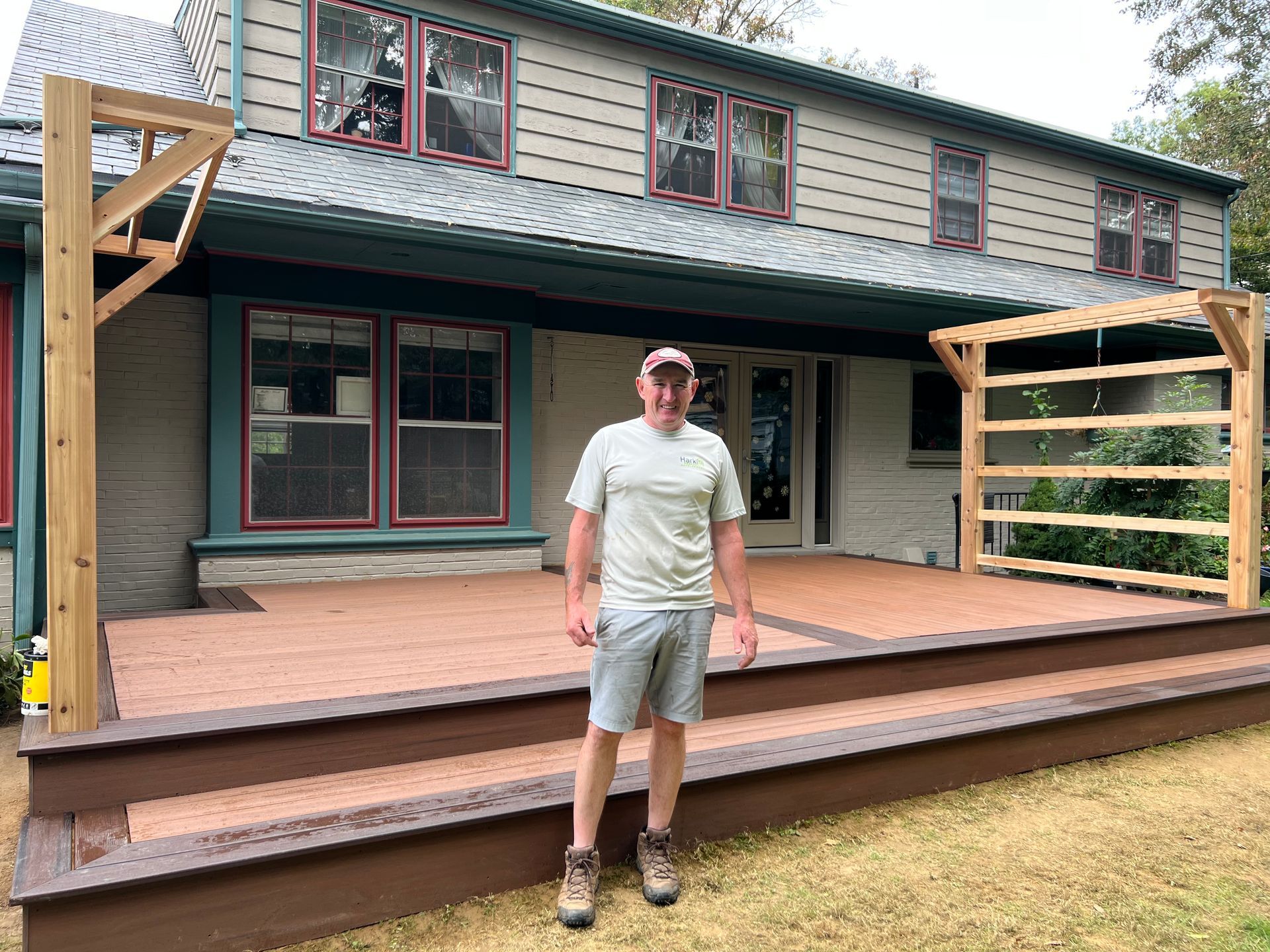 Lancaster PA Contractor stands on a newly built deck in front of a house, featuring wooden trellises on either side.