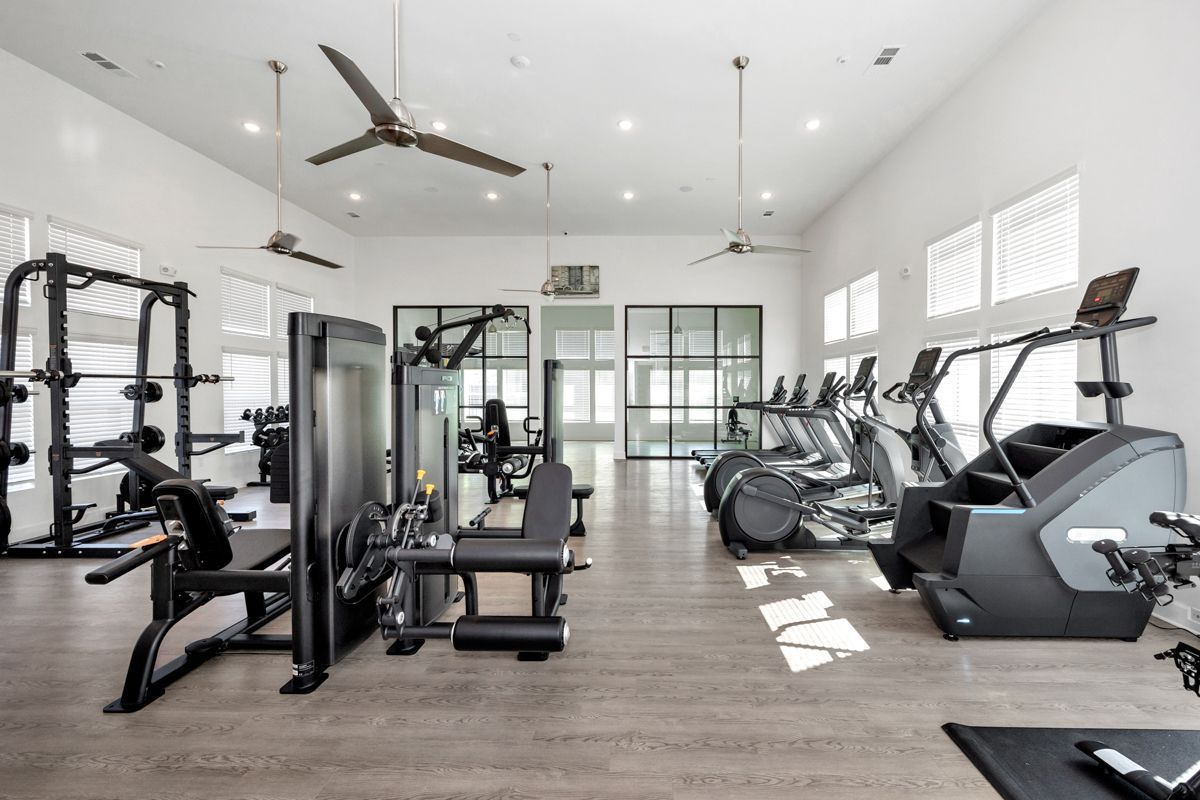 Gym interior with exercise machines, including weights and cardio equipment.