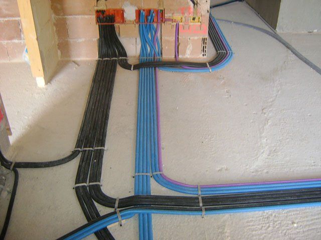 Durante i lavori di costruzione, fasci di cavi elettrici neri, blu e rosa sono stati posati lungo una parete e un pavimento.