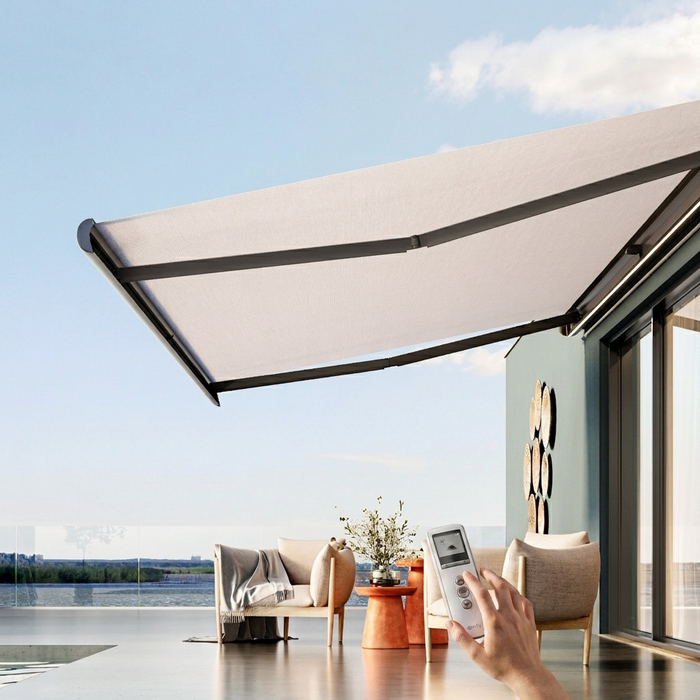Patio moderno con tenda da sole retrattile, vista lago, sedie a sdraio e una mano che impugna un telecomando.