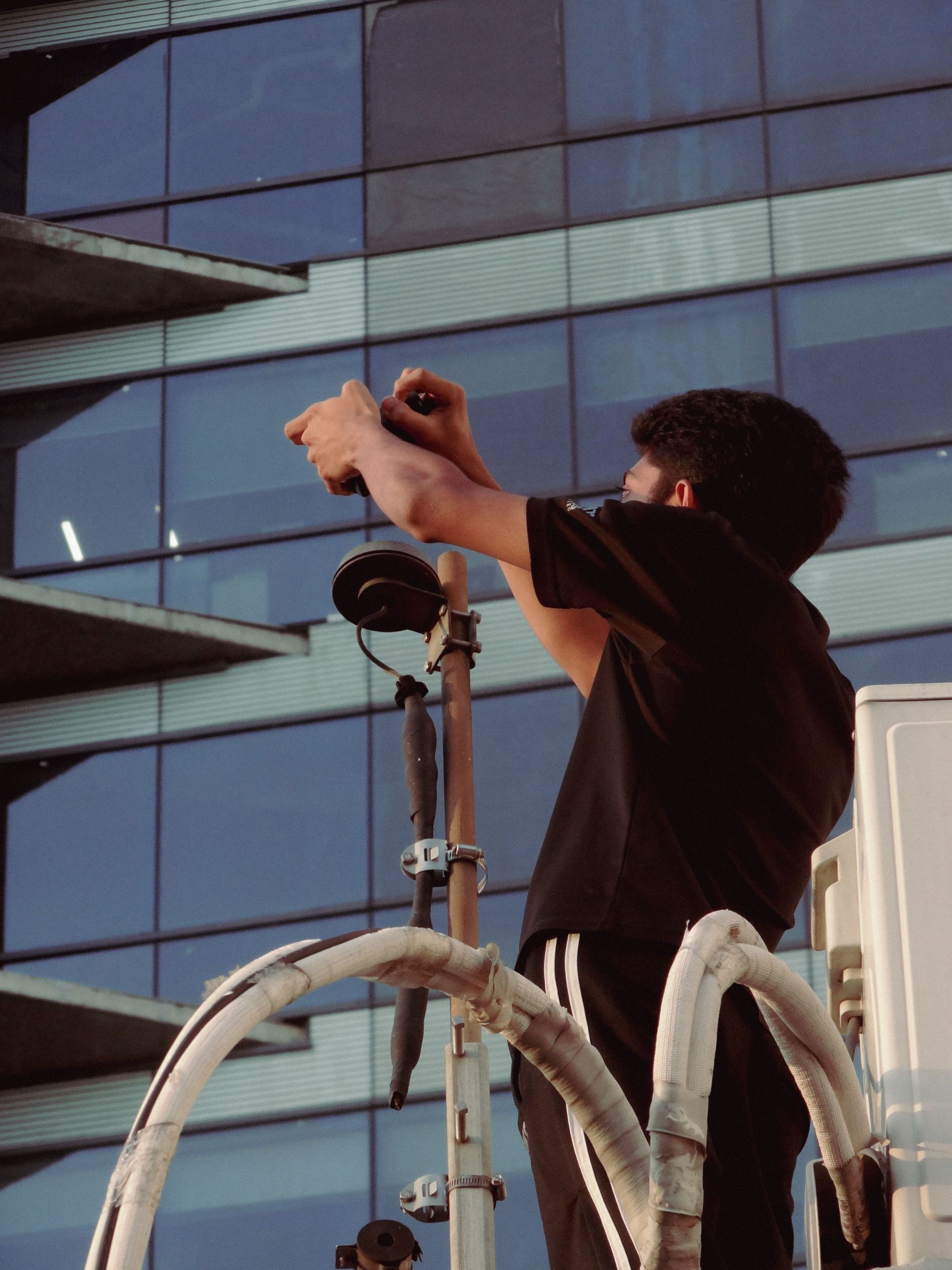 Una persona su una piattaforma rialzata regola una luce davanti a un edificio di vetro.