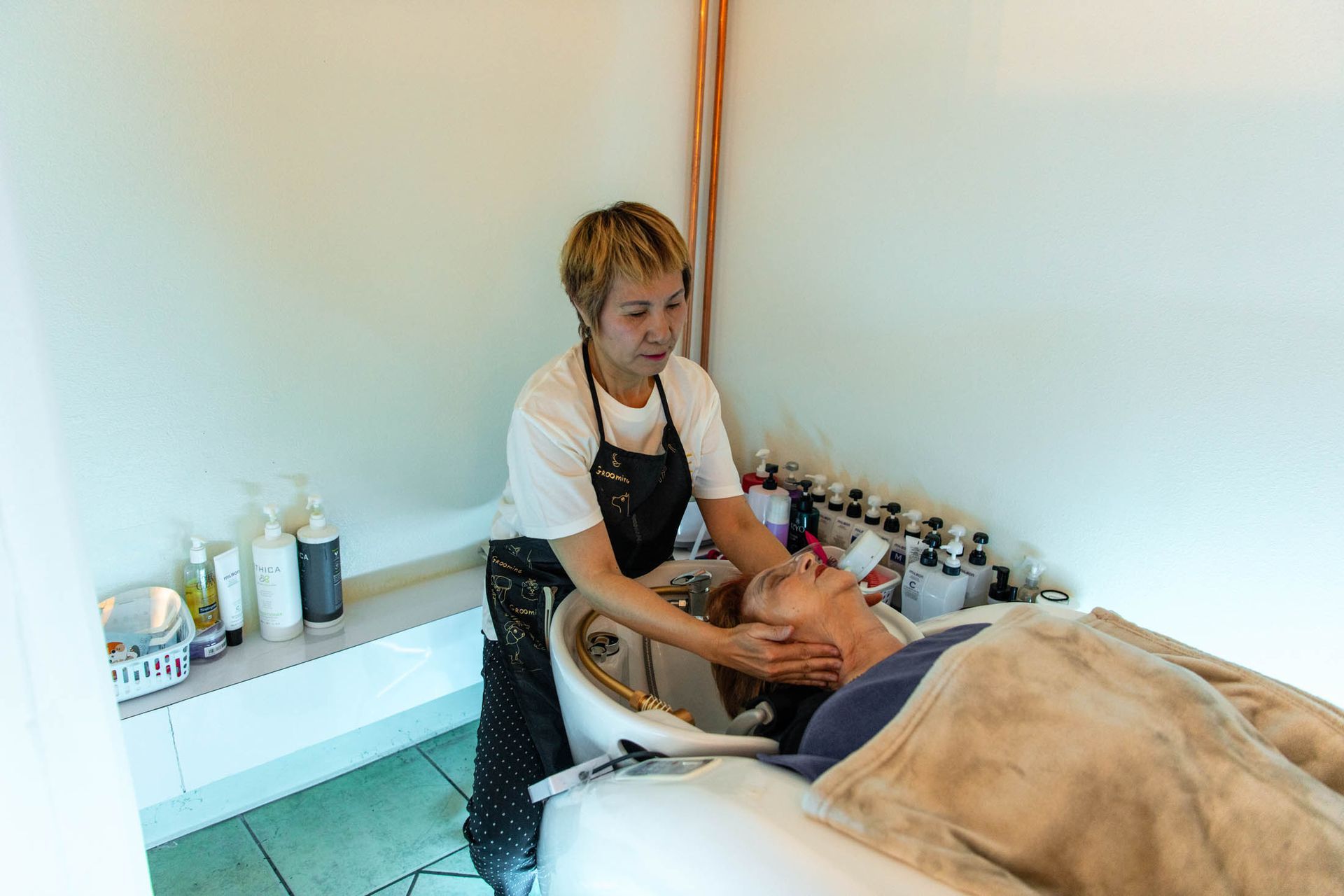 A professional stylist massages a client's neck at a hair salon wash station.