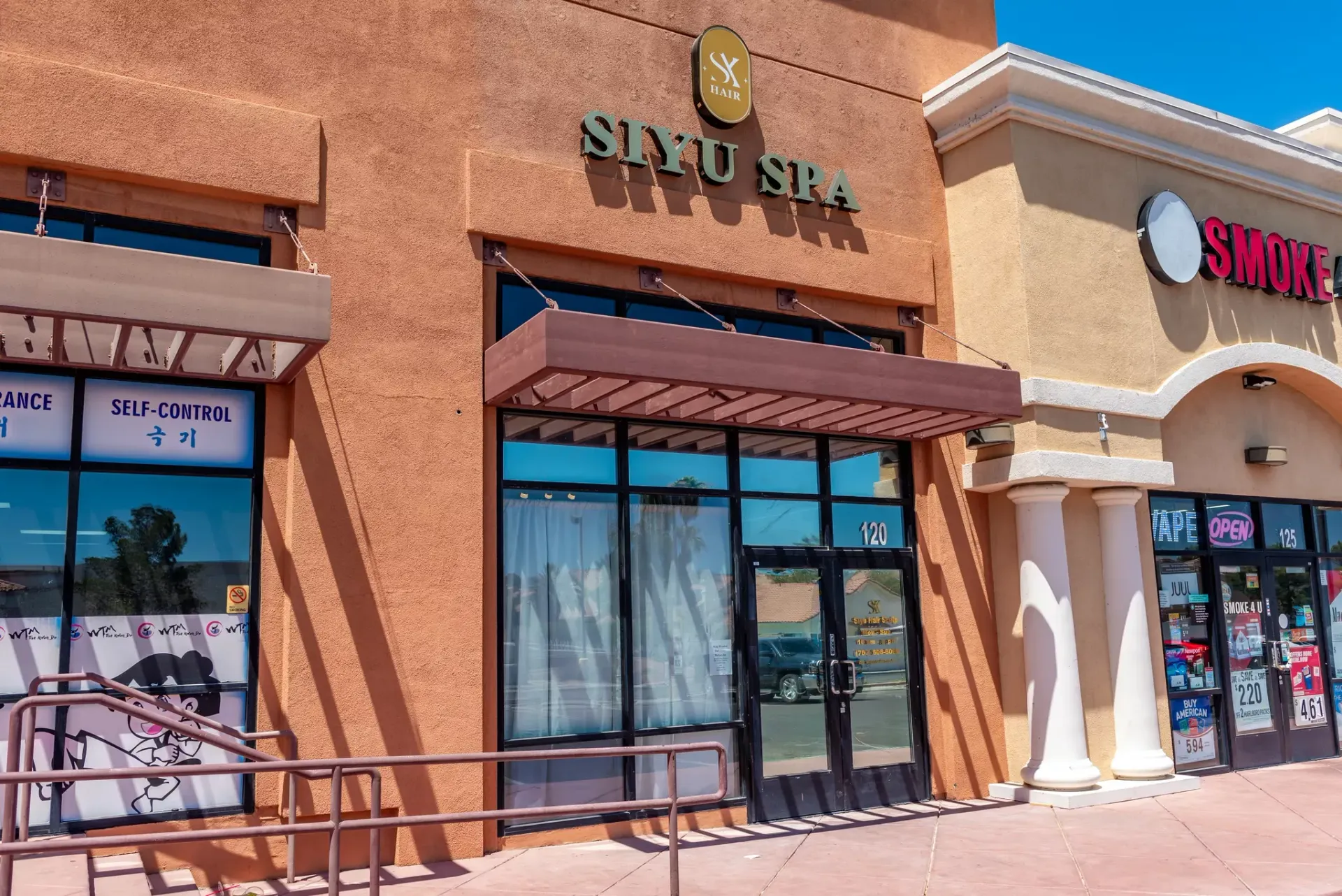 Exterior view of Siyu Spa storefront in a beige stucco retail strip center with a adjacent smoke shop.