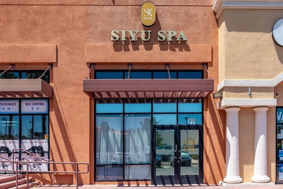 The storefront of Siyu Spa, featuring a tan stucco exterior, large glass windows, and a brown awning.
