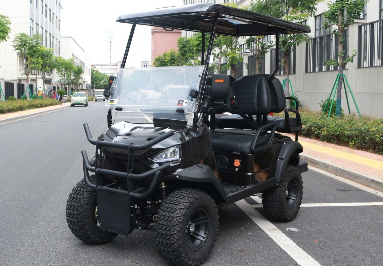 Carrito de golf negro con neumáticos grandes y toldo estacionado en la calle.