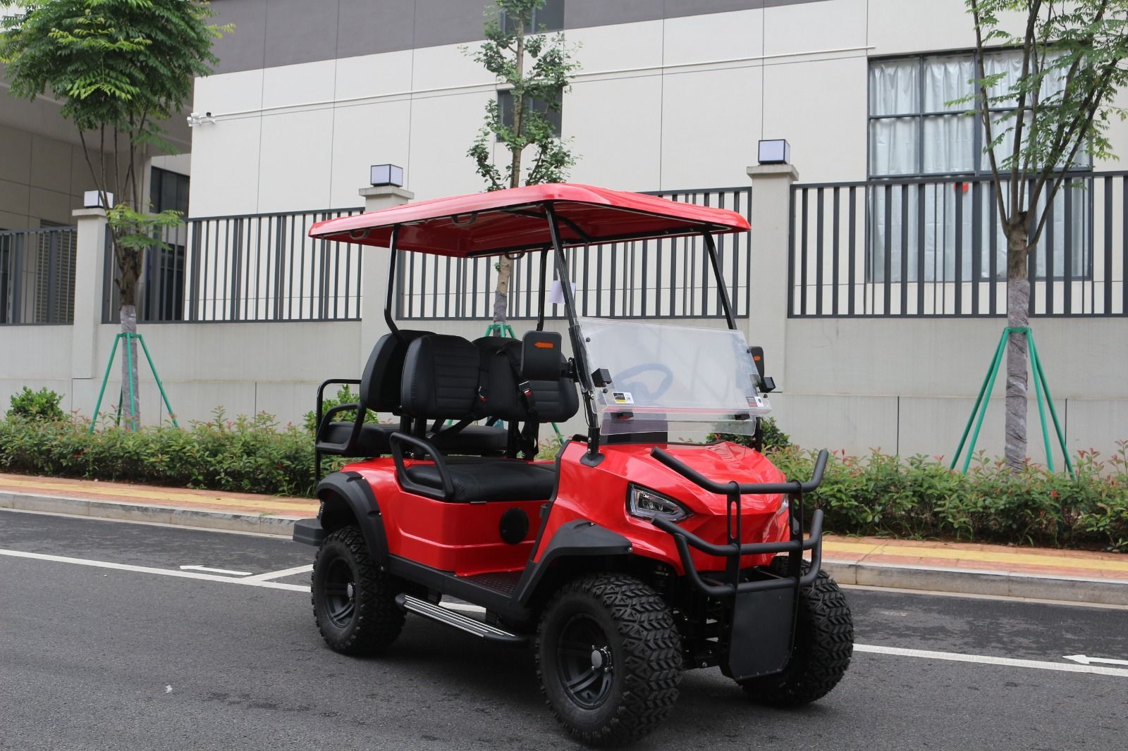 Un carrito de golf rojo con neumáticos negros estacionado en una calle frente a un edificio.