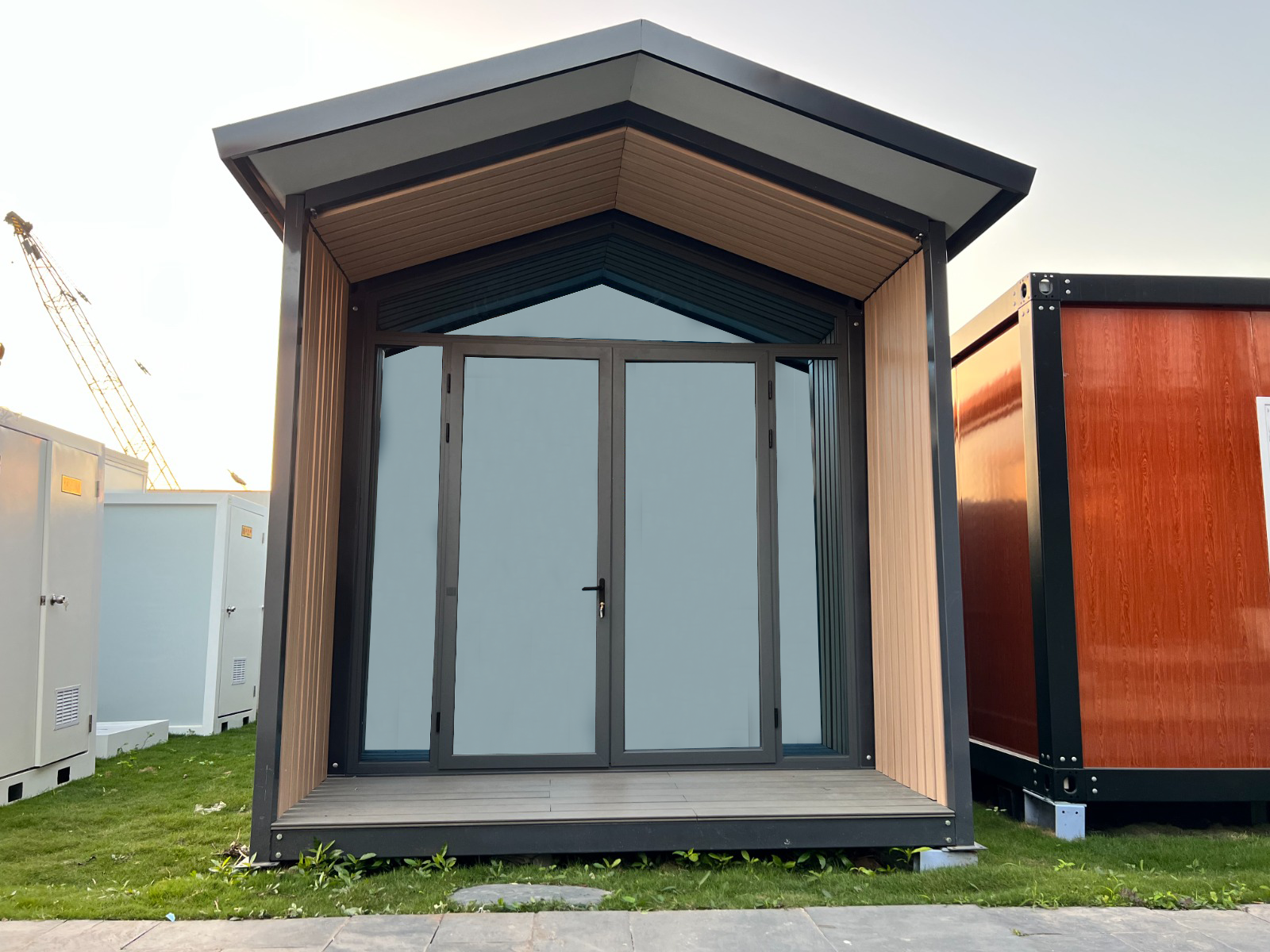 Pequeña cabaña moderna con puertas dobles de cristal, detalles de madera y techo oscuro.