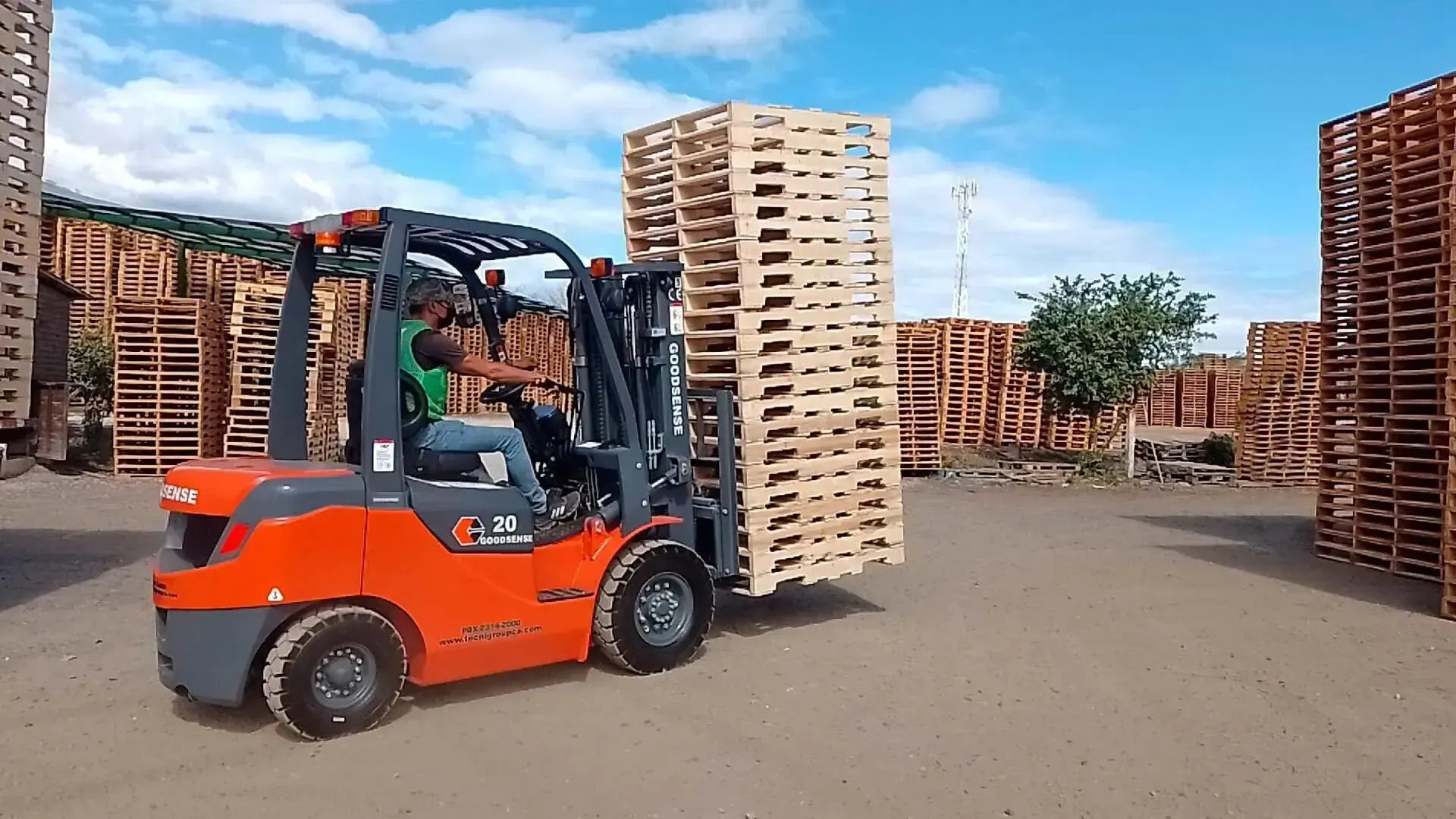 Una carretilla elevadora transporta una gran pila de palés de madera.