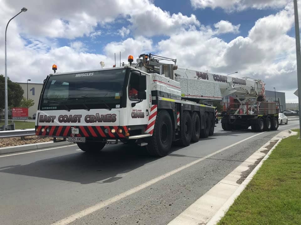 A Large Truck With a Crane on the Back is Driving Down a Road — East Coast Cranes in Coffs Harbour, NSW