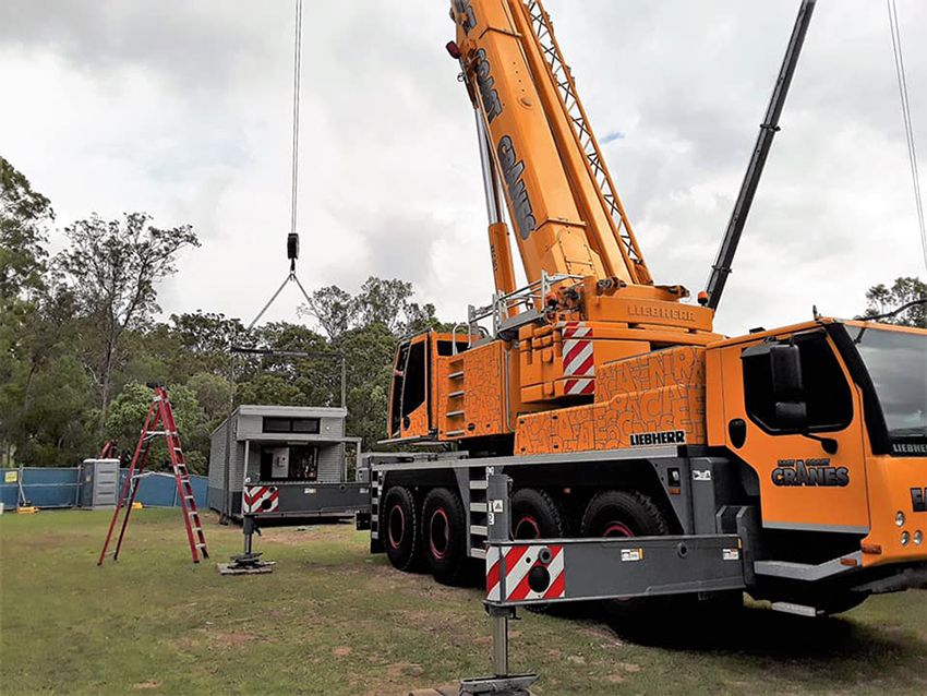 A Large Yellow Crane is Lifting a Building in a Field — East Coast Cranes in Rockhampton, QLD