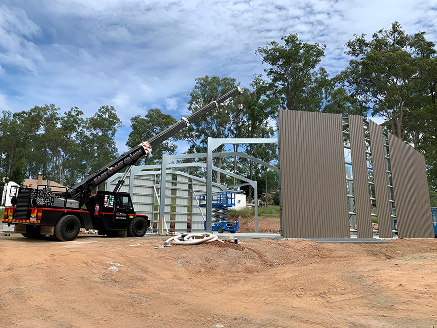 A Wall is Being Lifted by a Crane on a Construction Site — East Coast Cranes in Cairns, QLD