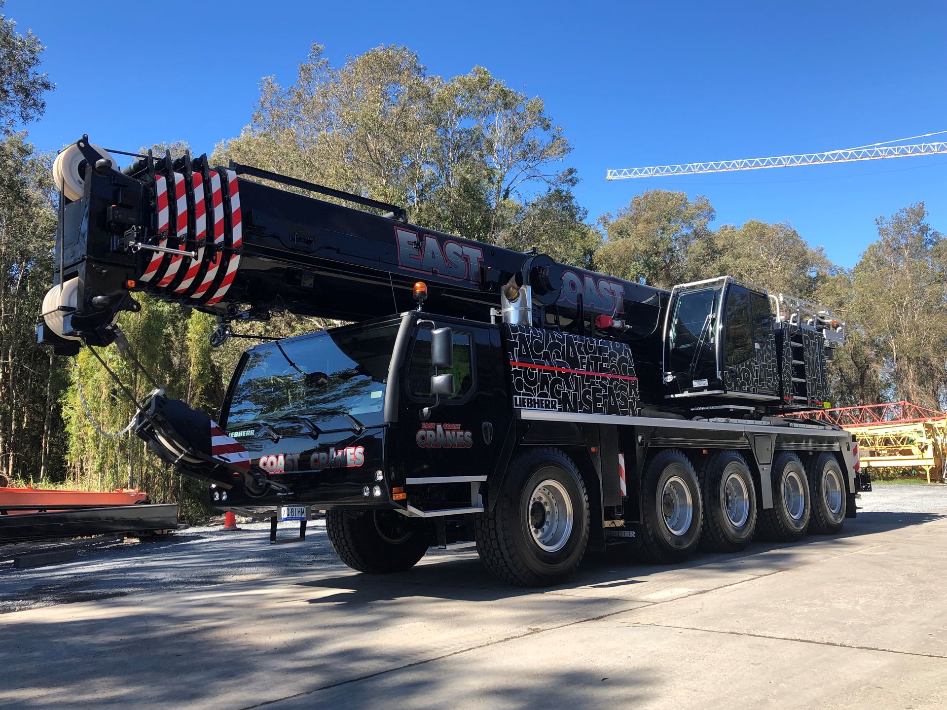 Black Mobile Crane on Asphalt, Boom Raised, Trees in Background — East Coast Cranes in Ormeau, QLD