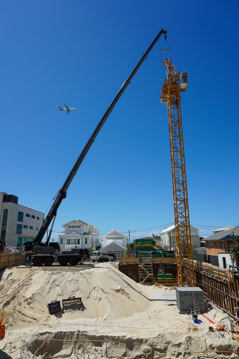 A Construction Site With a Crane and a Plane Flying in the Sky — East Coast Cranes in Gold Coast, QLD