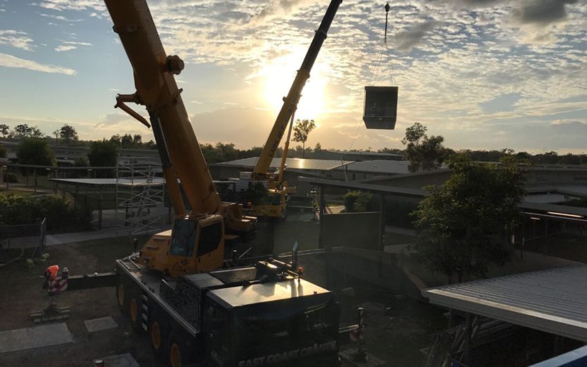 Two Cranes Lifting a Dark Container at a Construction Site — East Coast Cranes in Ormeau, QLD