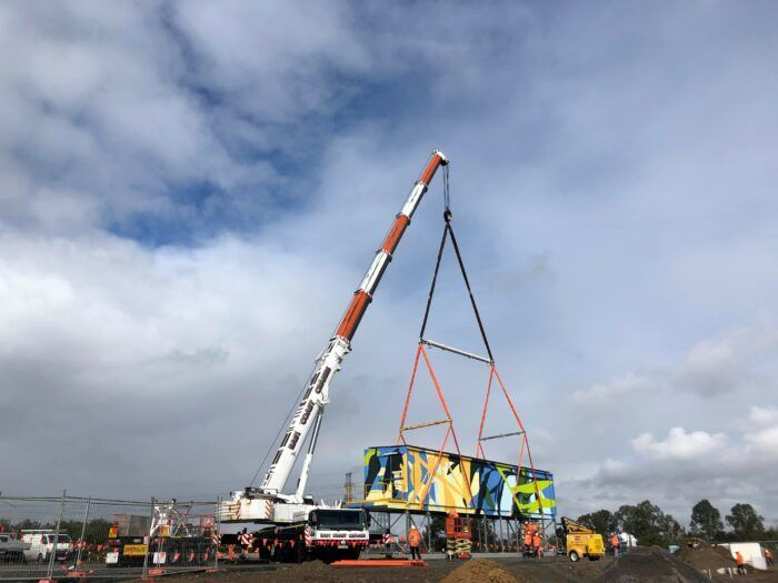 A Large Crane Is Lifting a Container on A Construction Site — East Coast Cranes in Ormeau, QLD