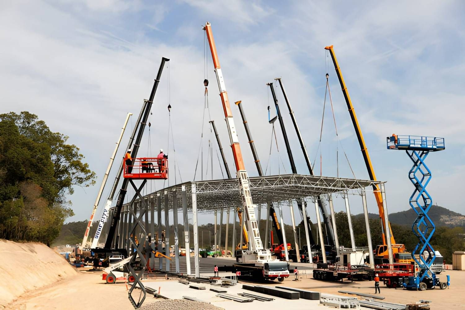 Construction Site With Multiple Cranes Erecting a Steel Frame Structure; Workers in Lifts and on the Ground — East Coast Cranes in Newcastle, NSW