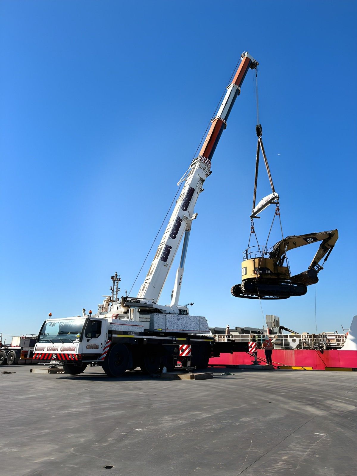 Large Crane Lifting an Excavator in a Sunny Outdoor Setting With a Clear Blue Sky — East Coast Cranes in Ormeau, QLD