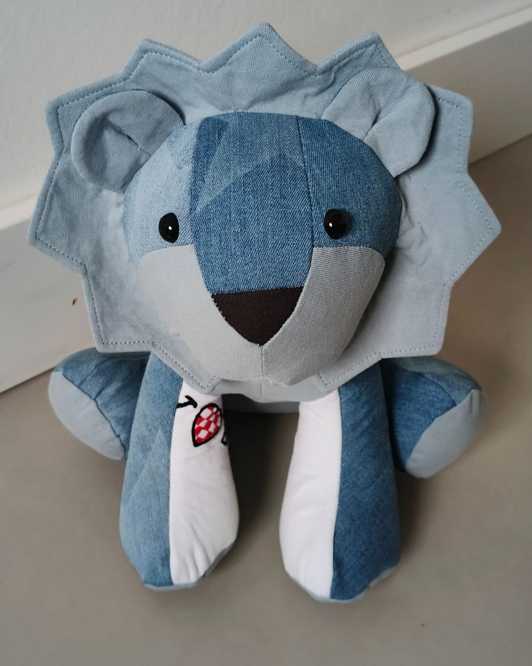 Blauwe troost leeuw van dierbare kleding met een witte manen en gestreepte poten op een tafel.