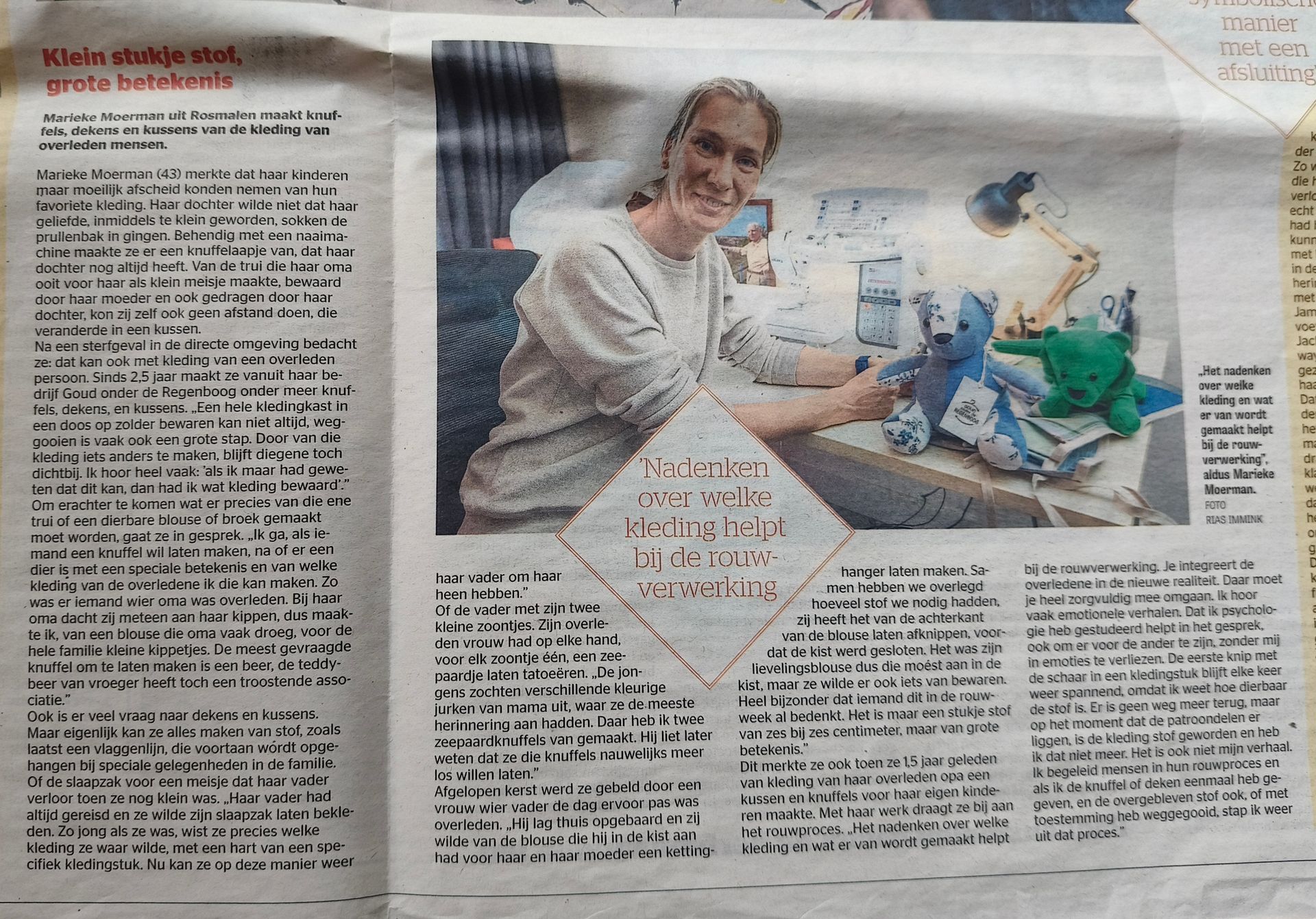 Een lachende vrouw zit aan een bureau knuffeldieren te naaien, zoals te zien is in een krantenartikel.