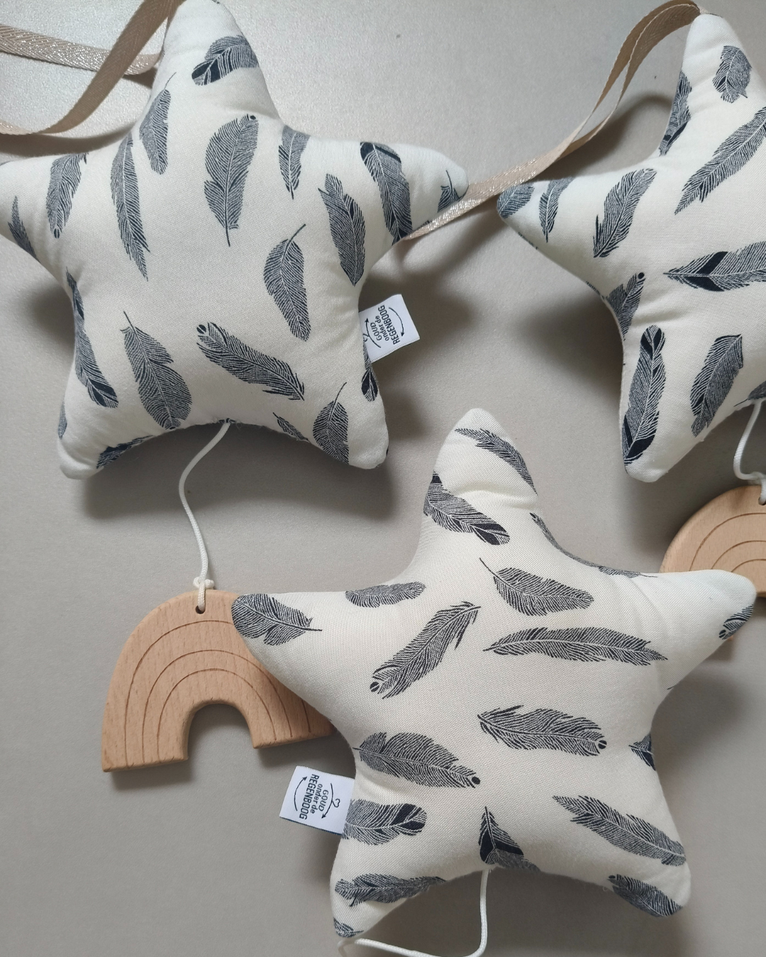 Twee stervormige stoffen ornamenten met beige regenbooglabels op een lichte achtergrond gemaakt van dierbare kleding.