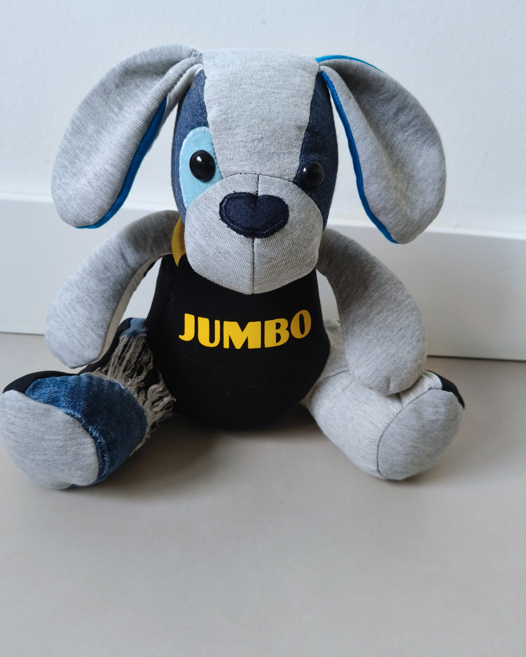 Grijs-zwarte pluche hond van kleding met een zwart shirt met gele