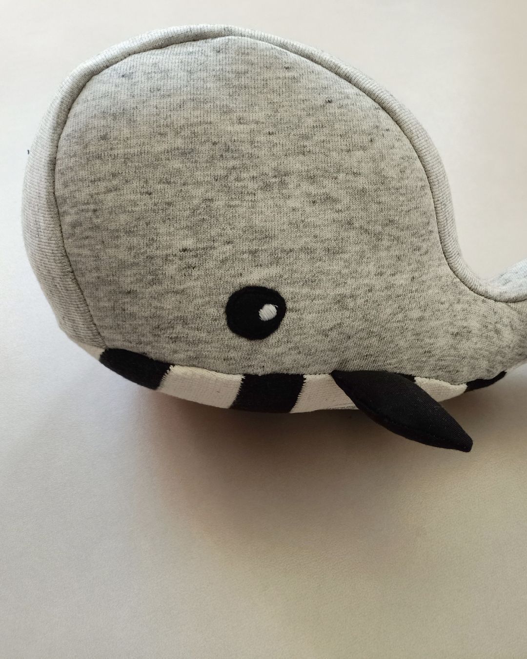 Een herinneringsknuffel in de vorm van een walvis op een wit oppervlak.