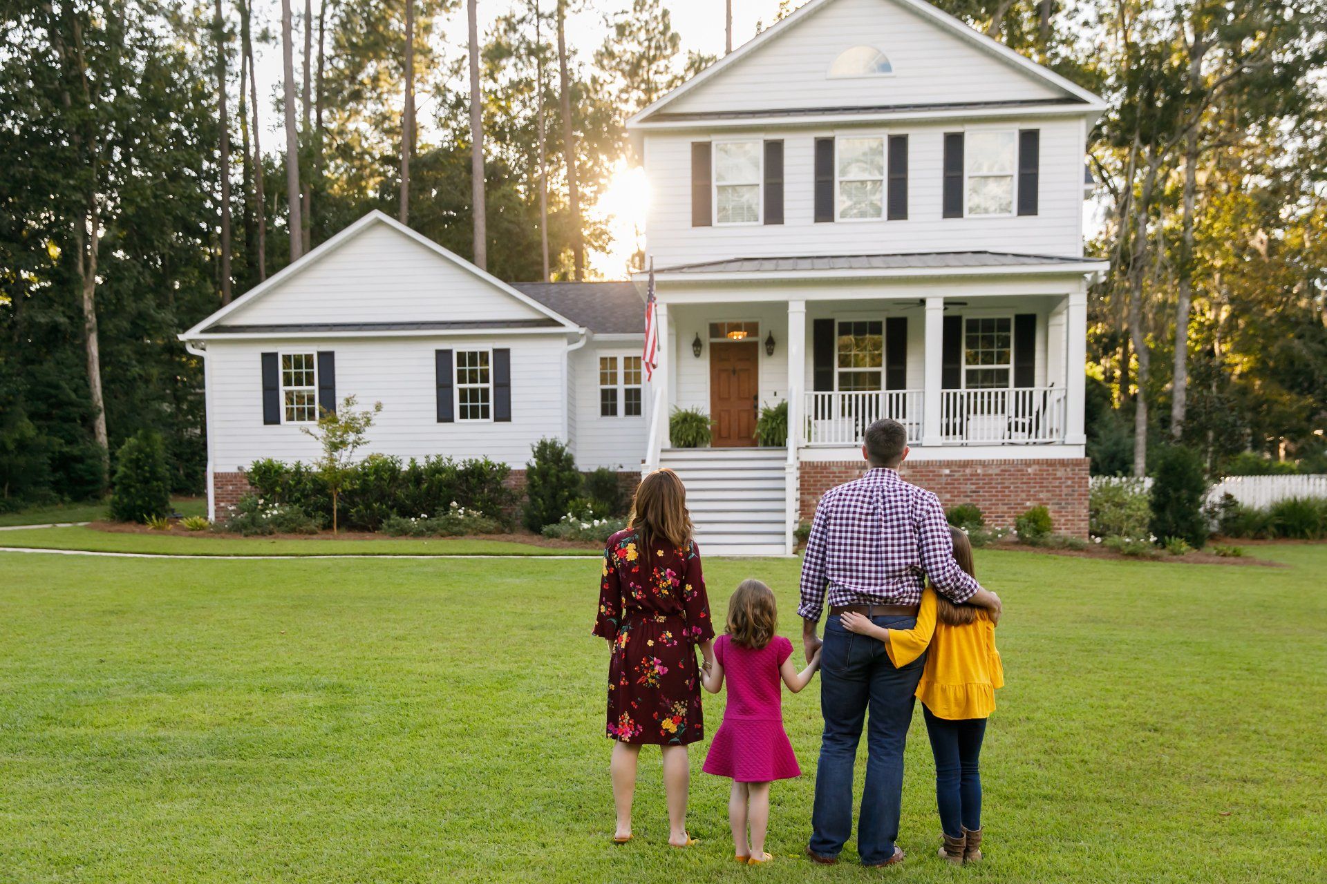 Una familia está parada frente a una gran casa blanca.