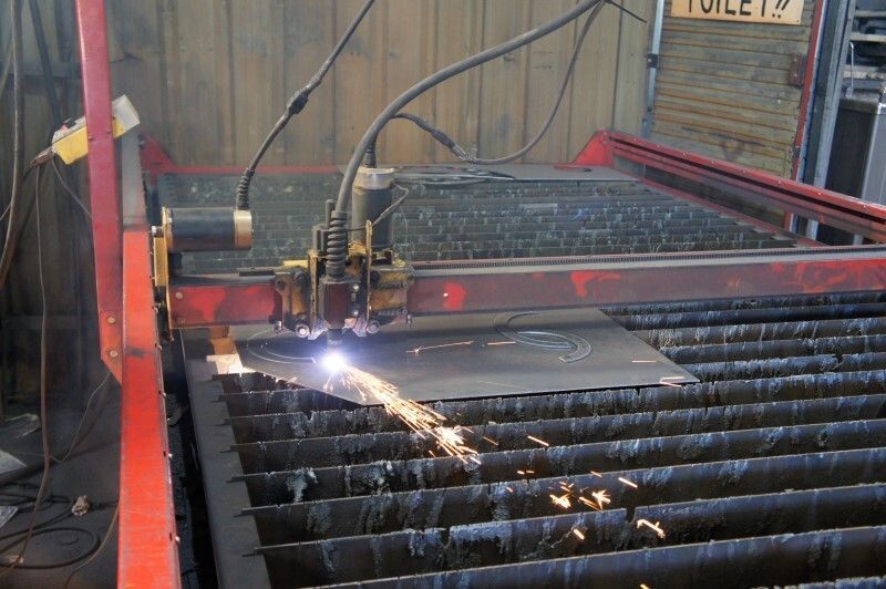 A man wearing a welding mask is welding a piece of metal.