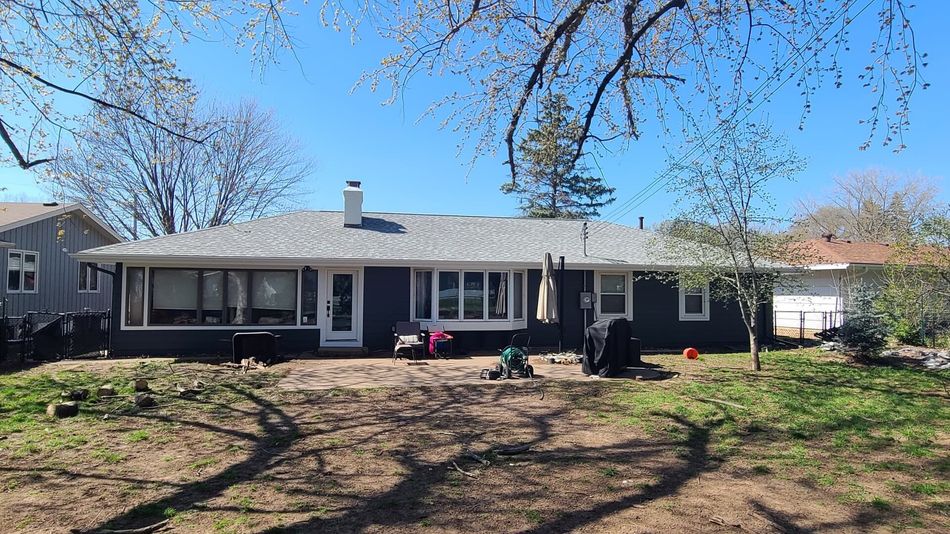 Wooden deck with stairs, built on a concrete patio, attached to a house with beige siding.