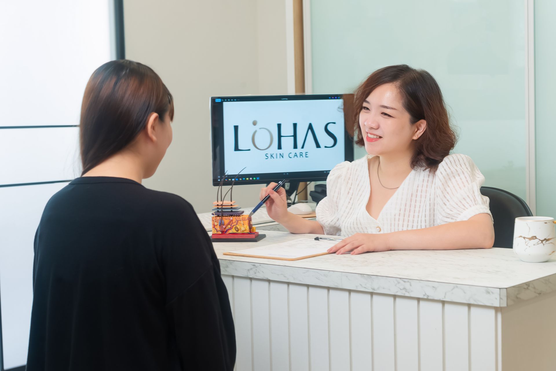 接待員在白色櫃檯前與訪客交談，背景中可以看到樂活（LOHAS）標誌。