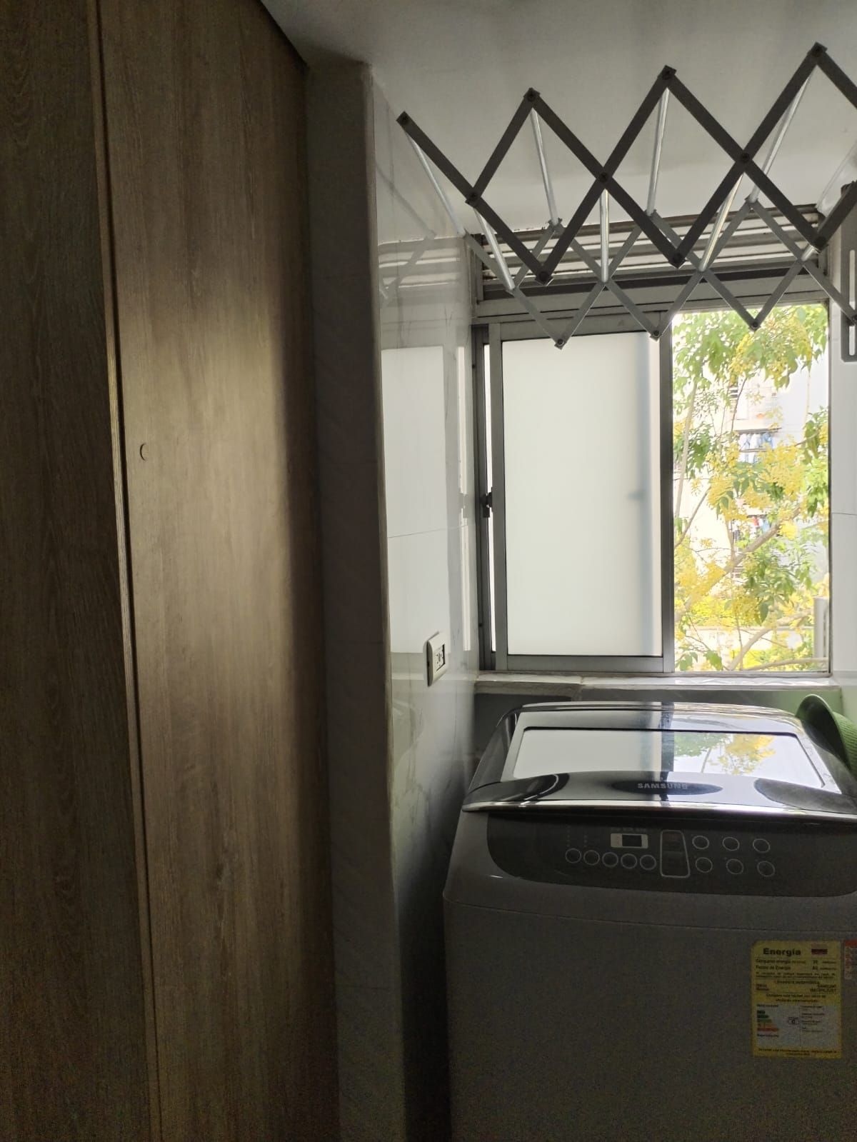 Una lavadora está en un lavadero al lado de una ventana.