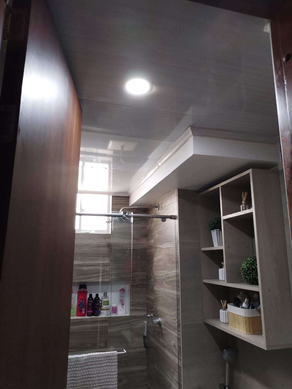 Un baño con puerta de ducha corrediza de vidrio y estantes.