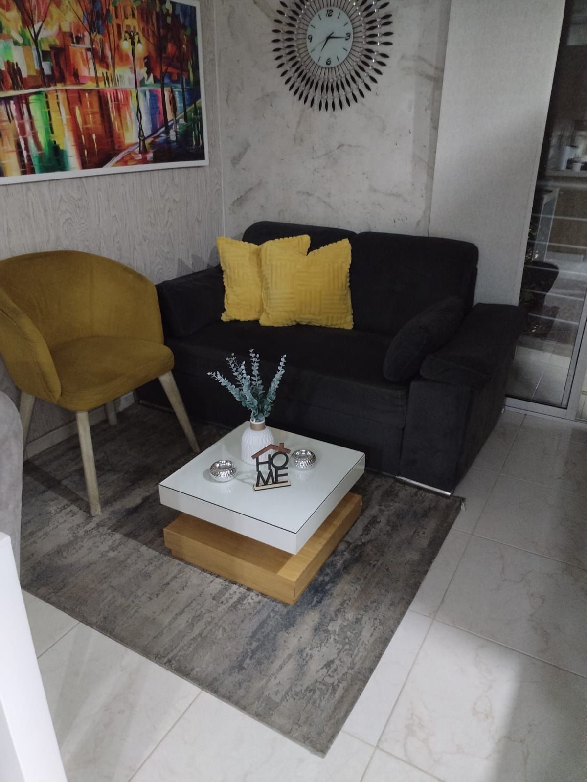 Una sala de estar con un sofá, una silla, una mesa de café y un reloj en la pared.