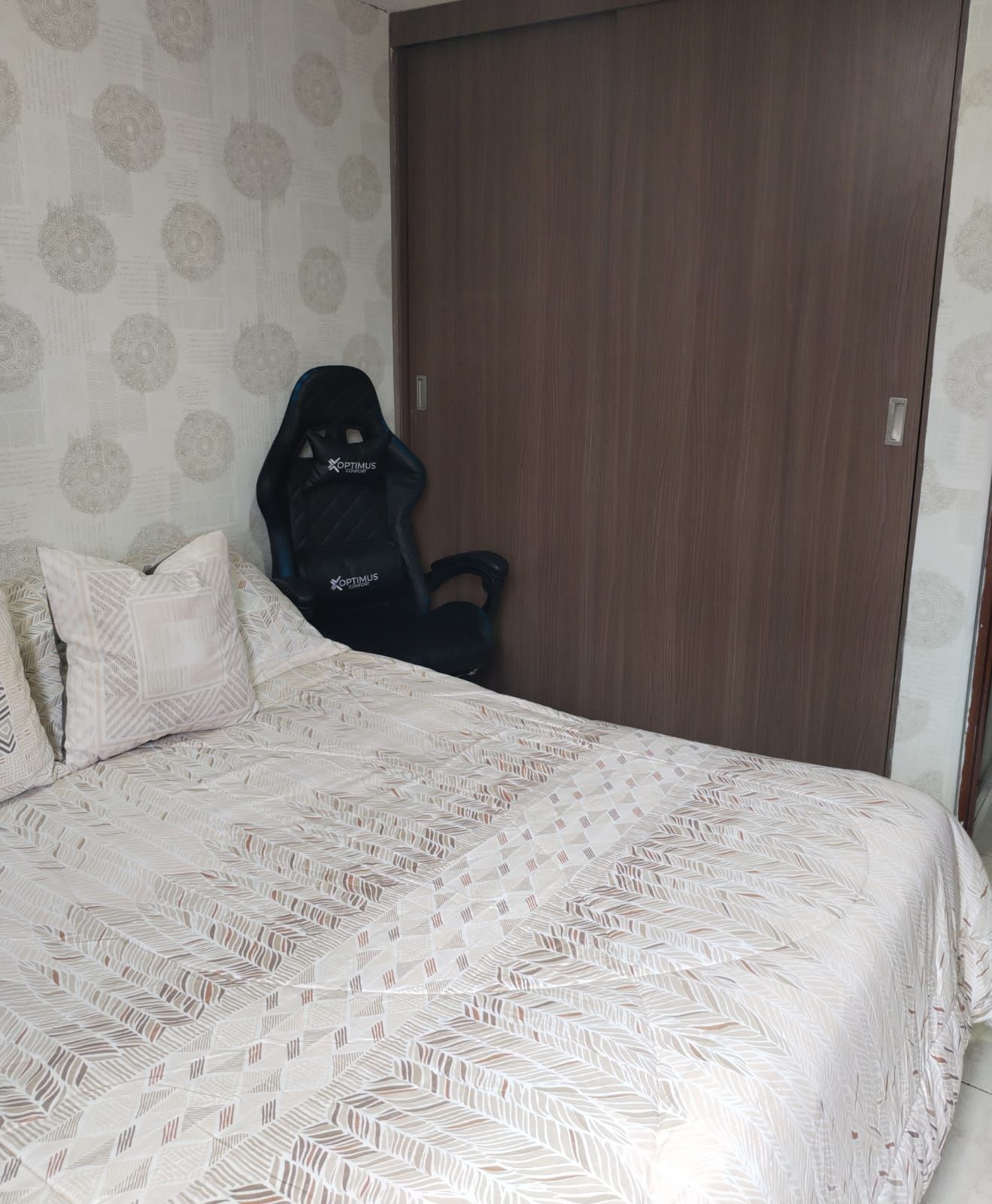 Un dormitorio con una cama, una silla y un armario.