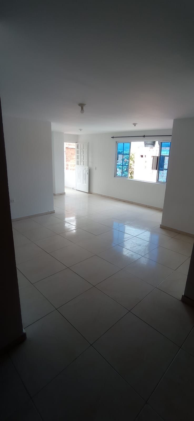 Una gran habitación vacía con una puerta corrediza de vidrio y dos ventanas.