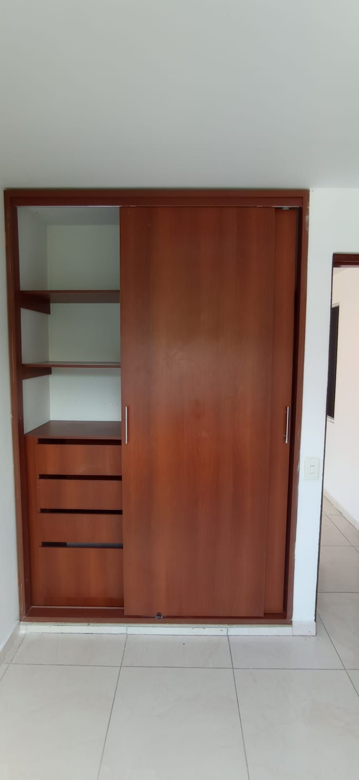 Un armario con puertas correderas y estantes en una habitación.